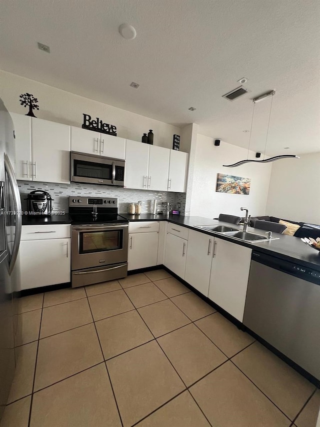 kitchen with backsplash, stainless steel appliances, tile patterned flooring, and white cabinets