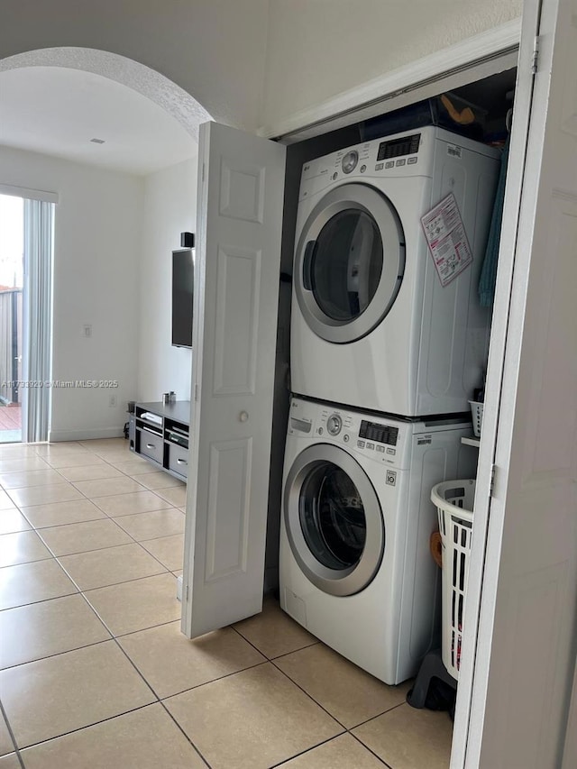 laundry room featuring light tile patterned floors and stacked washing maching and dryer