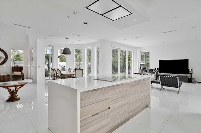 kitchen featuring pendant lighting, light brown cabinetry, a large island, black electric stovetop, and light tile patterned floors