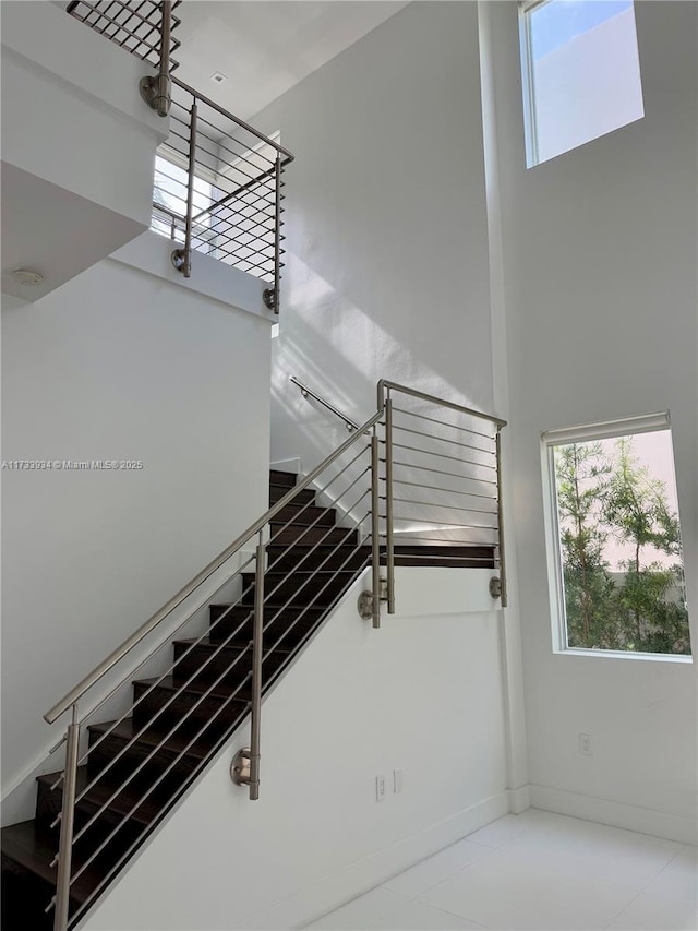 staircase with a high ceiling and a healthy amount of sunlight