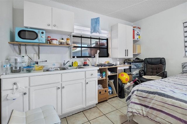 kitchen with light tile patterned flooring, sink, a textured ceiling, and white cabinets