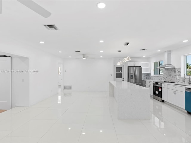 kitchen featuring sink, appliances with stainless steel finishes, white cabinetry, range hood, and decorative light fixtures