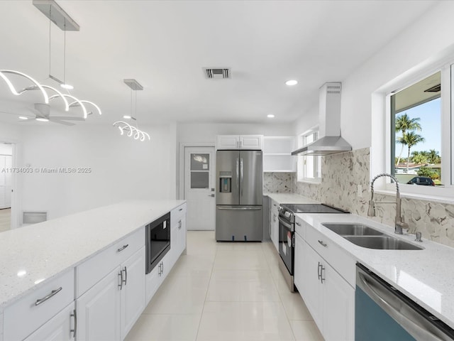 kitchen with pendant lighting, sink, appliances with stainless steel finishes, white cabinetry, and range hood