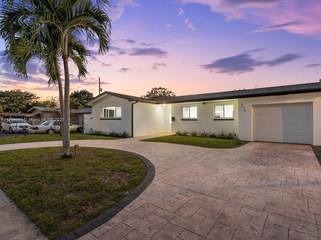 single story home featuring a garage and a lawn