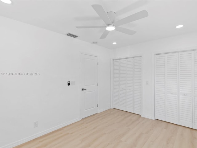 unfurnished bedroom featuring multiple closets, ceiling fan, and light hardwood / wood-style flooring