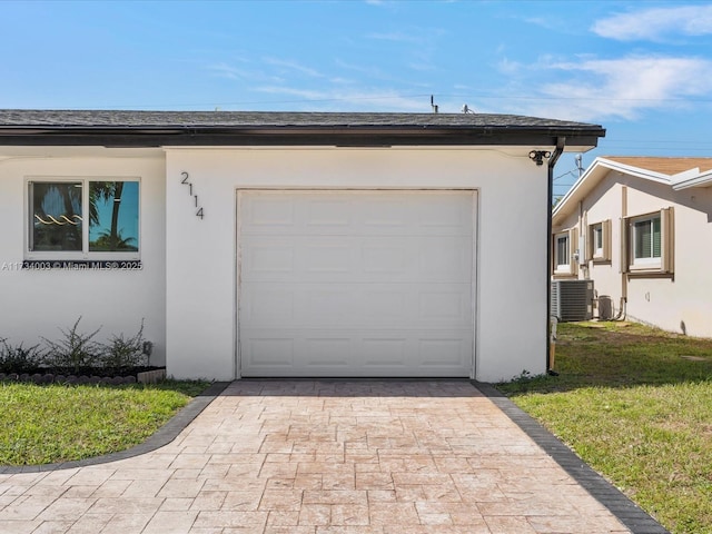 garage with a lawn and central air condition unit