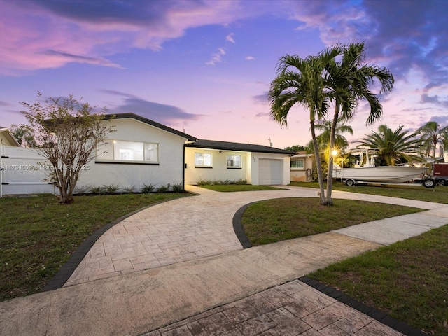 single story home featuring a garage and a lawn