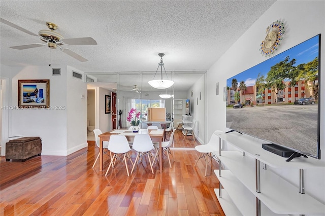 dining room with ceiling fan, a textured ceiling, and light wood-type flooring