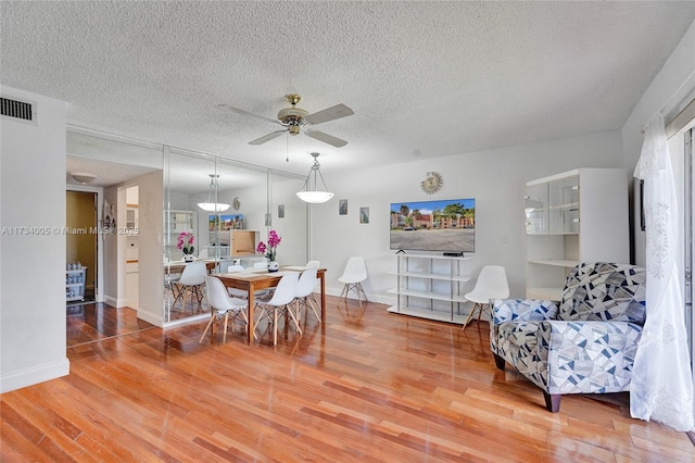 dining space with ceiling fan, hardwood / wood-style floors, and a textured ceiling