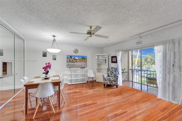 dining area with ceiling fan, hardwood / wood-style floors, and a textured ceiling