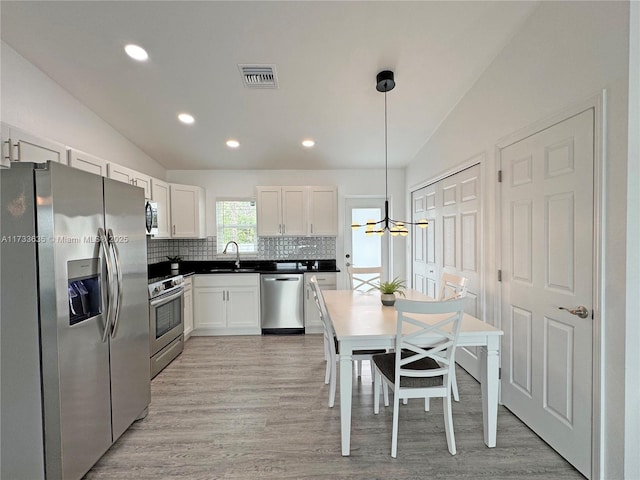 kitchen with lofted ceiling, stainless steel appliances, sink, and hanging light fixtures