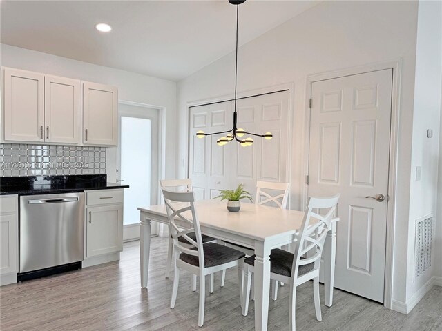 dining room featuring vaulted ceiling, an inviting chandelier, and light hardwood / wood-style flooring