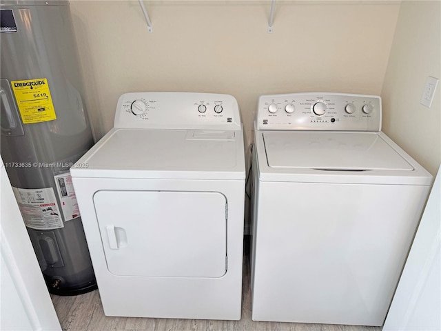 clothes washing area featuring independent washer and dryer, water heater, and light wood-type flooring