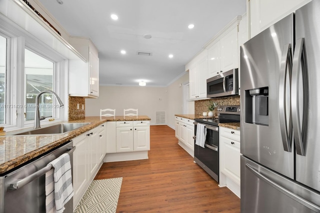 kitchen with stone counters, stainless steel appliances, tasteful backsplash, and white cabinets