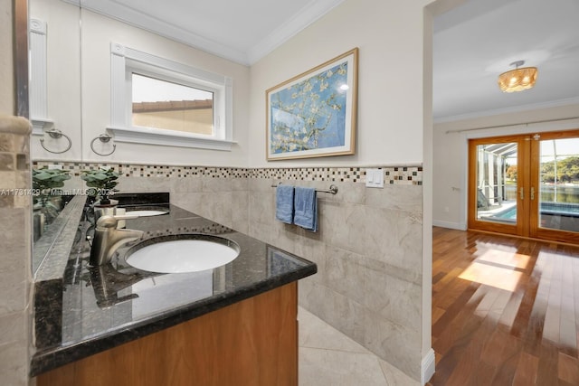 bathroom featuring french doors, tile walls, ornamental molding, vanity, and hardwood / wood-style floors