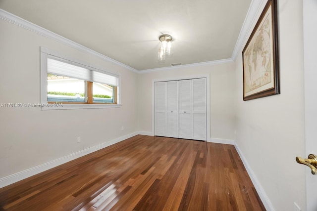 unfurnished bedroom with crown molding, hardwood / wood-style floors, and a closet