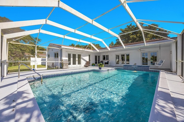 view of pool with french doors, area for grilling, a lanai, ceiling fan, and a patio area