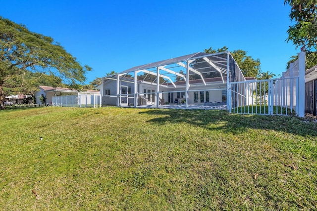 rear view of property featuring a yard and glass enclosure