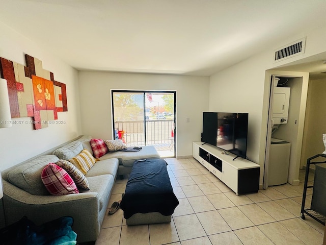 tiled living room featuring stacked washer / drying machine