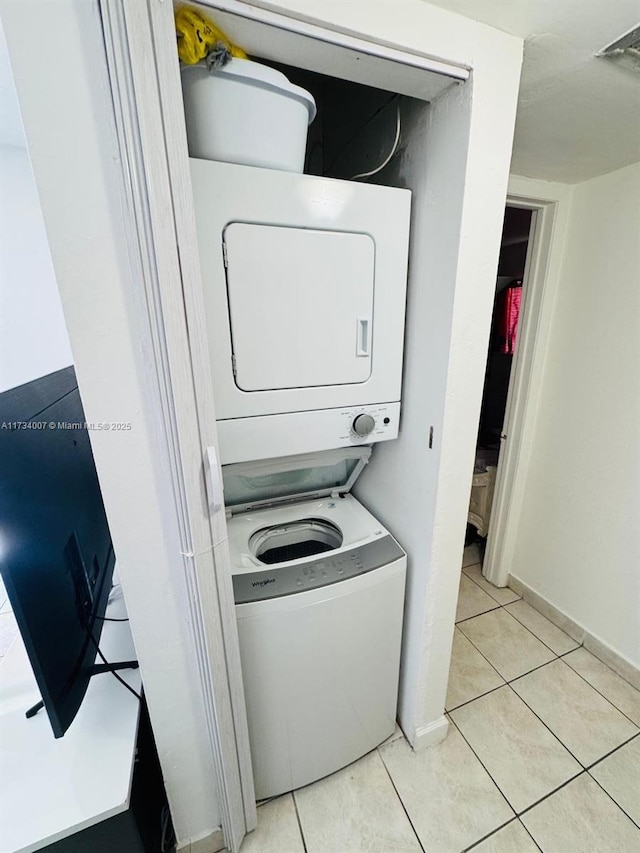 laundry area featuring light tile patterned flooring and stacked washer / drying machine