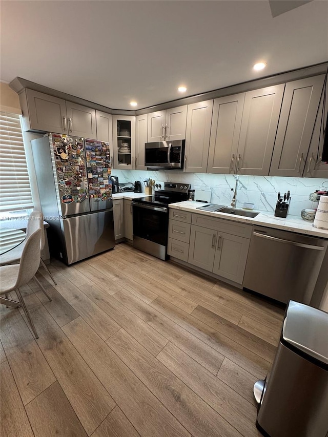 kitchen featuring light hardwood / wood-style floors, appliances with stainless steel finishes, gray cabinets, and sink