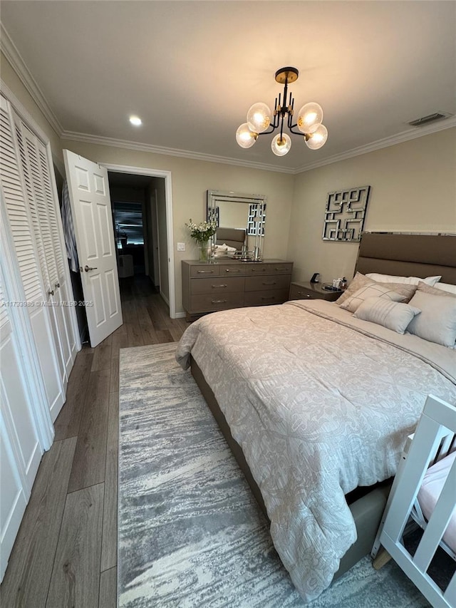 bedroom featuring dark hardwood / wood-style flooring, ornamental molding, and an inviting chandelier