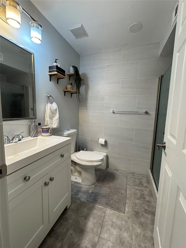 bathroom with tile patterned flooring, tile walls, vanity, an enclosed shower, and toilet