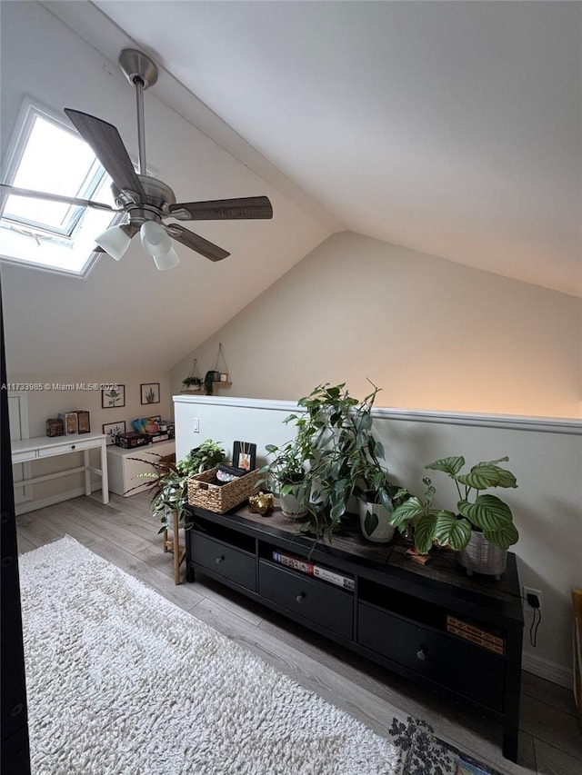 sitting room featuring ceiling fan, light hardwood / wood-style floors, and vaulted ceiling with skylight