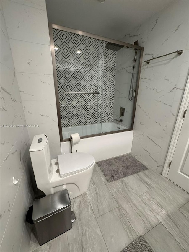 bathroom with combined bath / shower with glass door and toilet