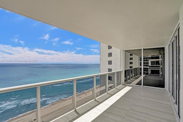 balcony featuring a water view and a beach view