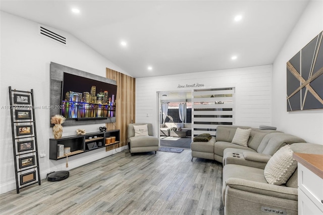 living room with hardwood / wood-style flooring, vaulted ceiling, and wood walls