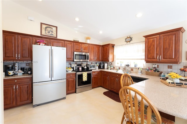 kitchen with tasteful backsplash, light countertops, appliances with stainless steel finishes, vaulted ceiling, and a sink