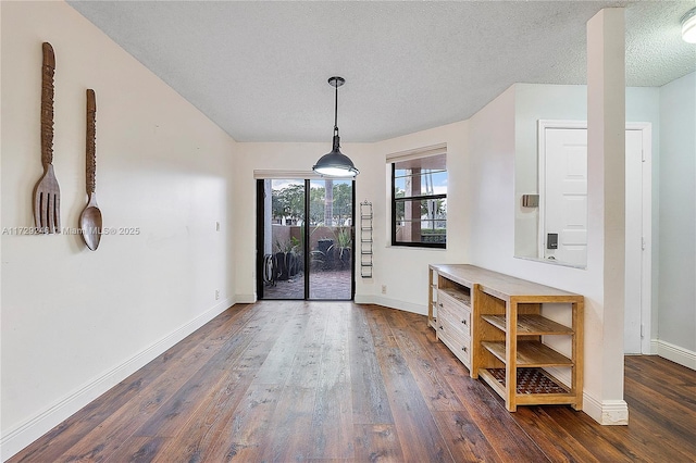 unfurnished dining area with dark hardwood / wood-style floors and a textured ceiling