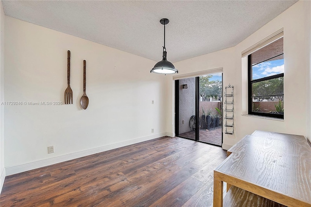 unfurnished dining area with dark wood-type flooring and a textured ceiling