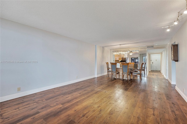 unfurnished dining area with dark wood-type flooring and a textured ceiling