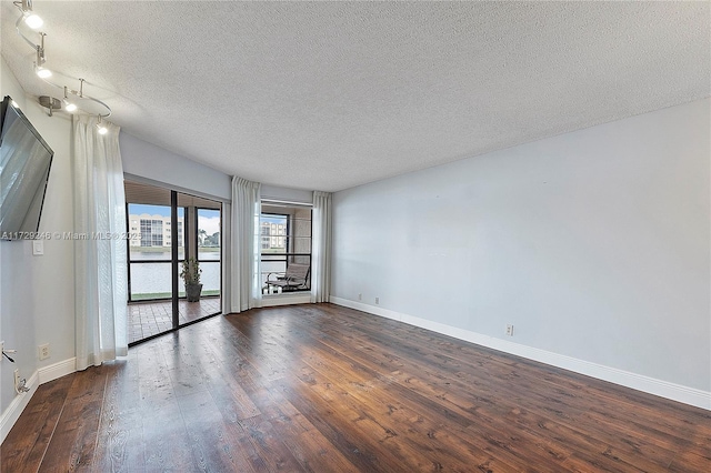 spare room featuring dark hardwood / wood-style flooring and a textured ceiling