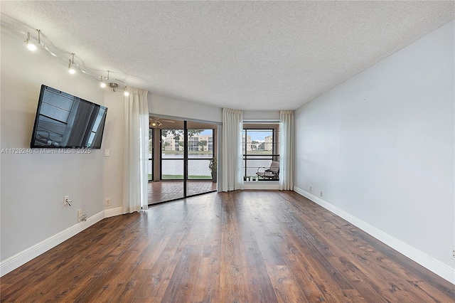 unfurnished room with dark hardwood / wood-style floors and a textured ceiling