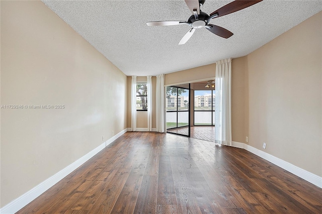 empty room featuring dark wood-type flooring, ceiling fan, and a textured ceiling