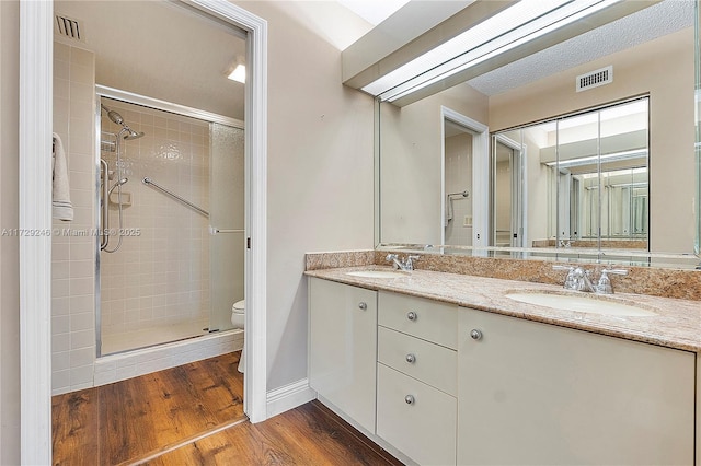 bathroom featuring vanity, hardwood / wood-style floors, a shower with door, and toilet