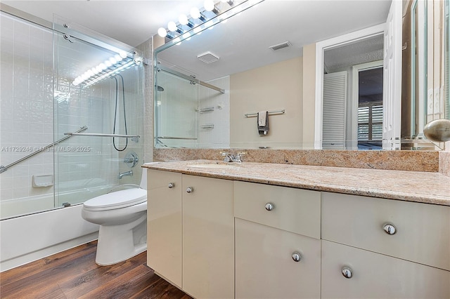 full bathroom featuring enclosed tub / shower combo, vanity, hardwood / wood-style floors, and toilet