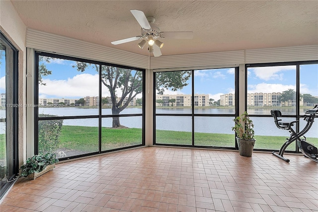 unfurnished sunroom with ceiling fan and a water view