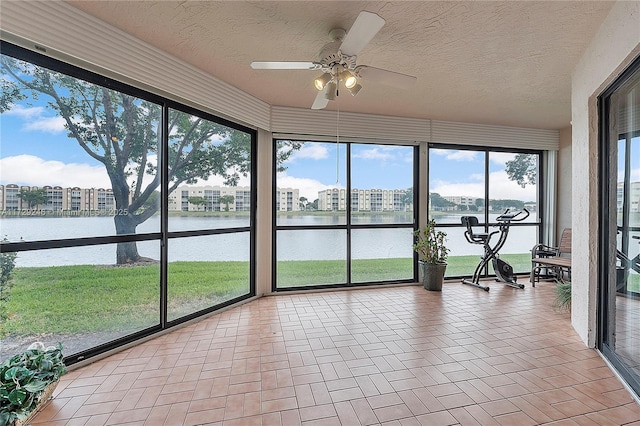 unfurnished sunroom featuring a water view, ceiling fan, and a healthy amount of sunlight