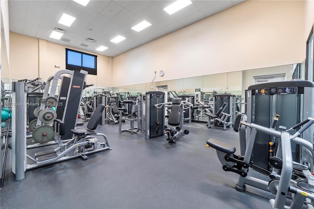 workout area featuring a drop ceiling and a high ceiling