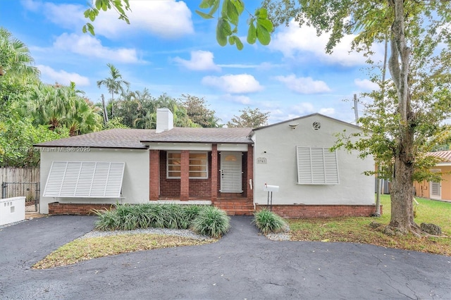 single story home with aphalt driveway, a chimney, and stucco siding