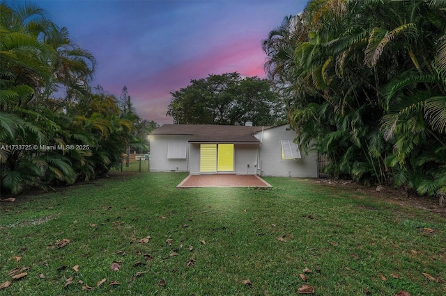 rear view of property with fence, a lawn, a patio, and stucco siding