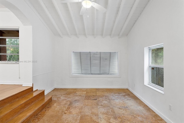 spare room with arched walkways, beamed ceiling, and baseboards