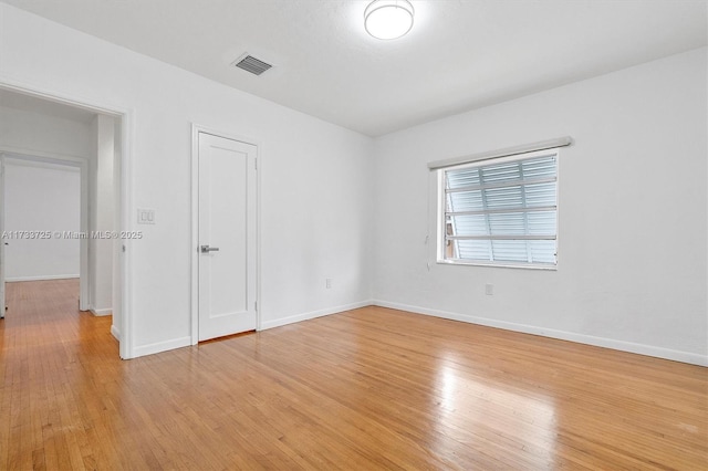 spare room featuring light wood finished floors, baseboards, and visible vents