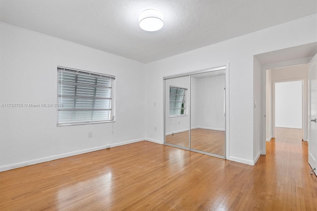 unfurnished bedroom with a closet, light wood-type flooring, and baseboards