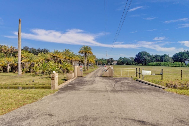 view of road with aphalt driveway, a gate, a rural view, and a gated entry