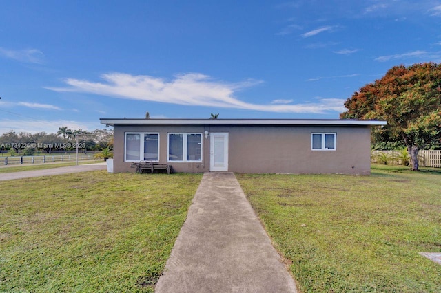 view of front of property with a front yard, fence, and stucco siding